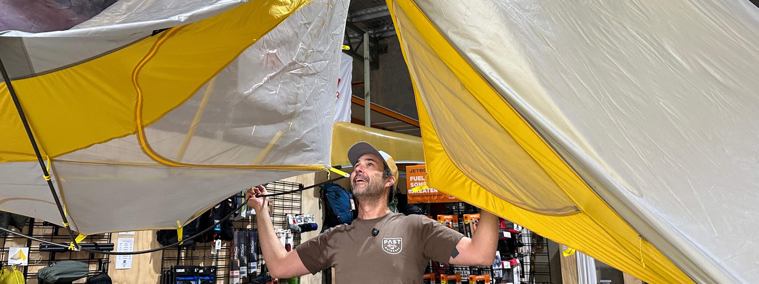 Man holding two yellow grey mont moondance tents smiling