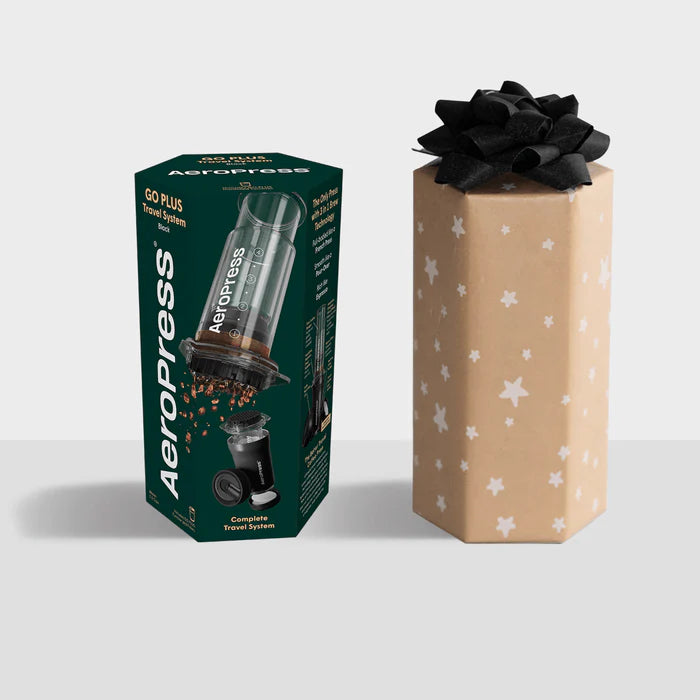 Aeropress coffee maker packaging next to a gift box with a black bow on a white background