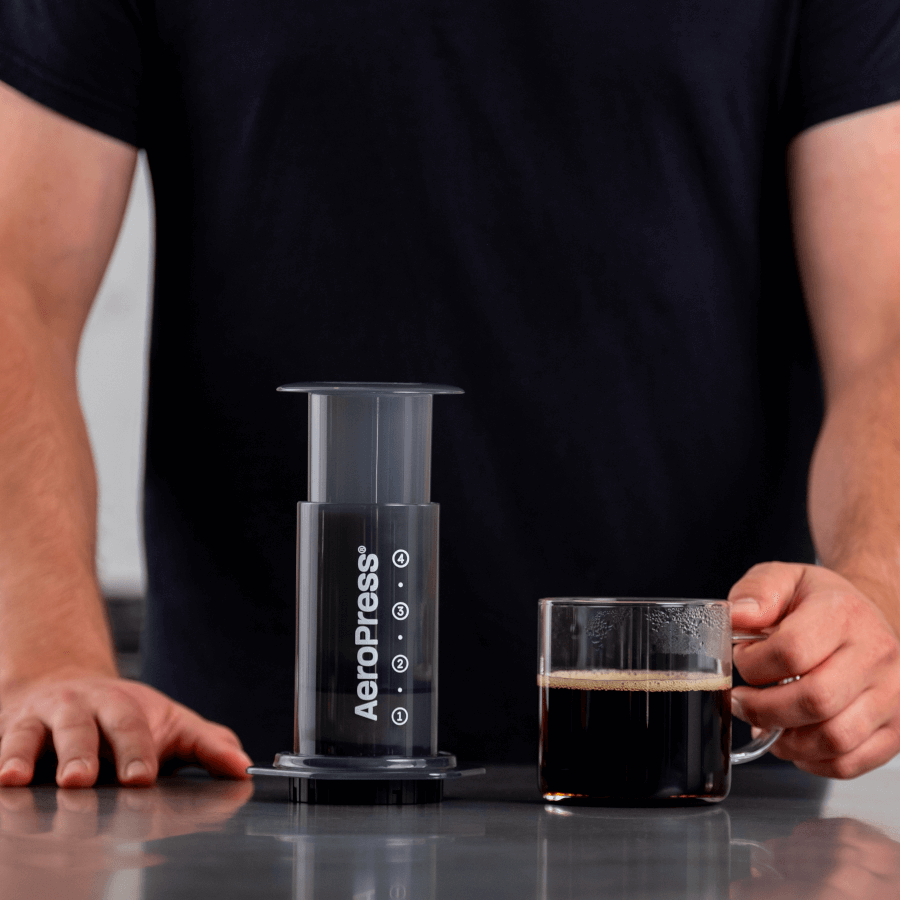 Aeropress_Original_coffee_maker next to a freshly made cup of coffee