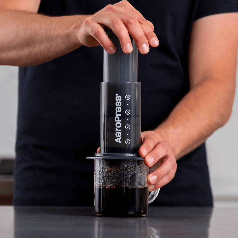 A barista making a coffee with an aeropress portable coffee maker
