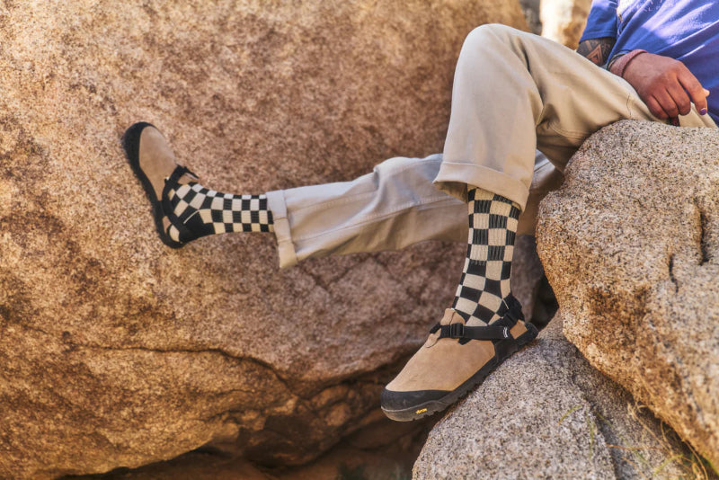 Person wearing checkered socks and hiking boots sitting on a rock