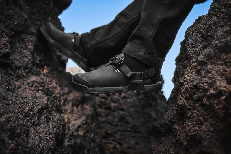 Person wearing black shoes with straps on rocky terrain