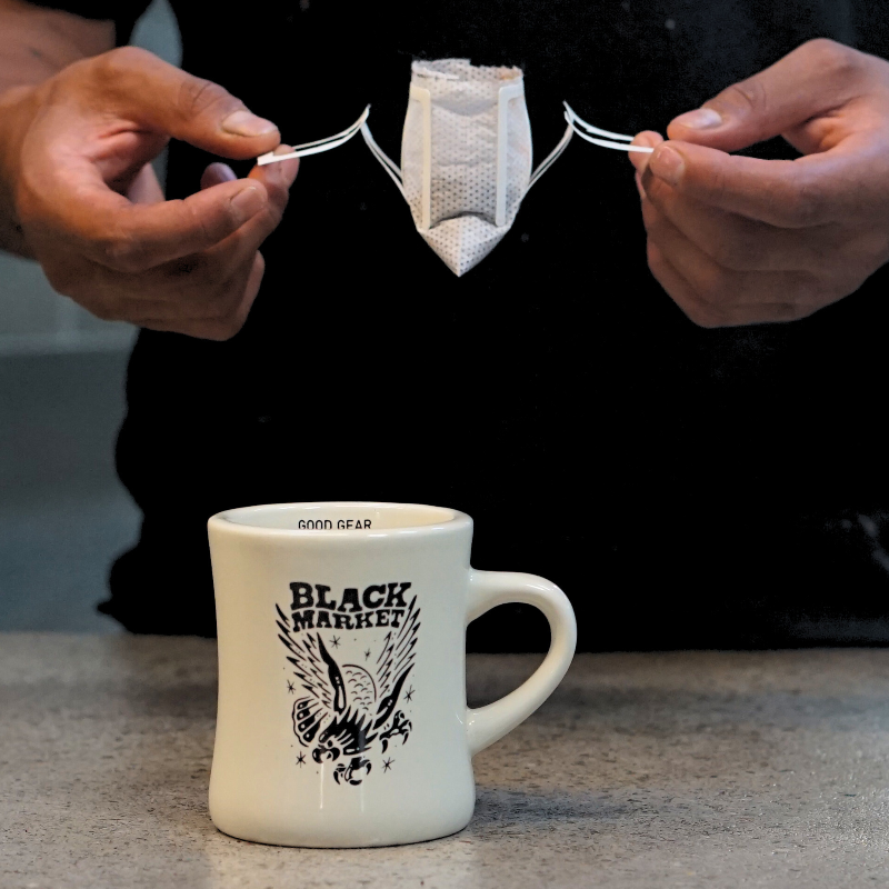 A black market coffee bag being opened ready to be placed on a coffee cup