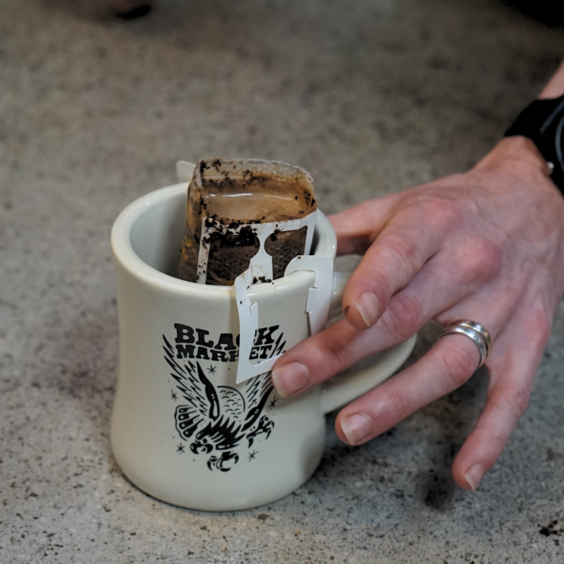 Black Market Coffee baggie with coffee being made in a cup
