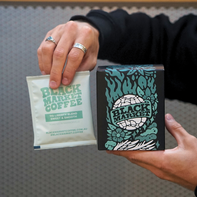 A black Market Coffee drip bag and the box of ten packaing on a grey background