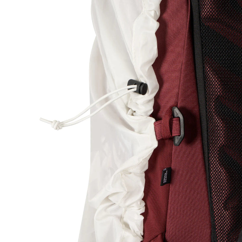 Close-up of a backpack with a white drawstring and red back panel.