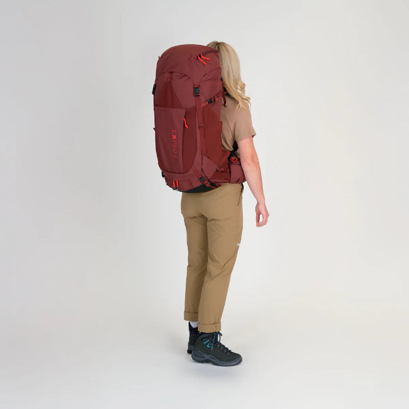 Person wearing a large red backpack on a white background