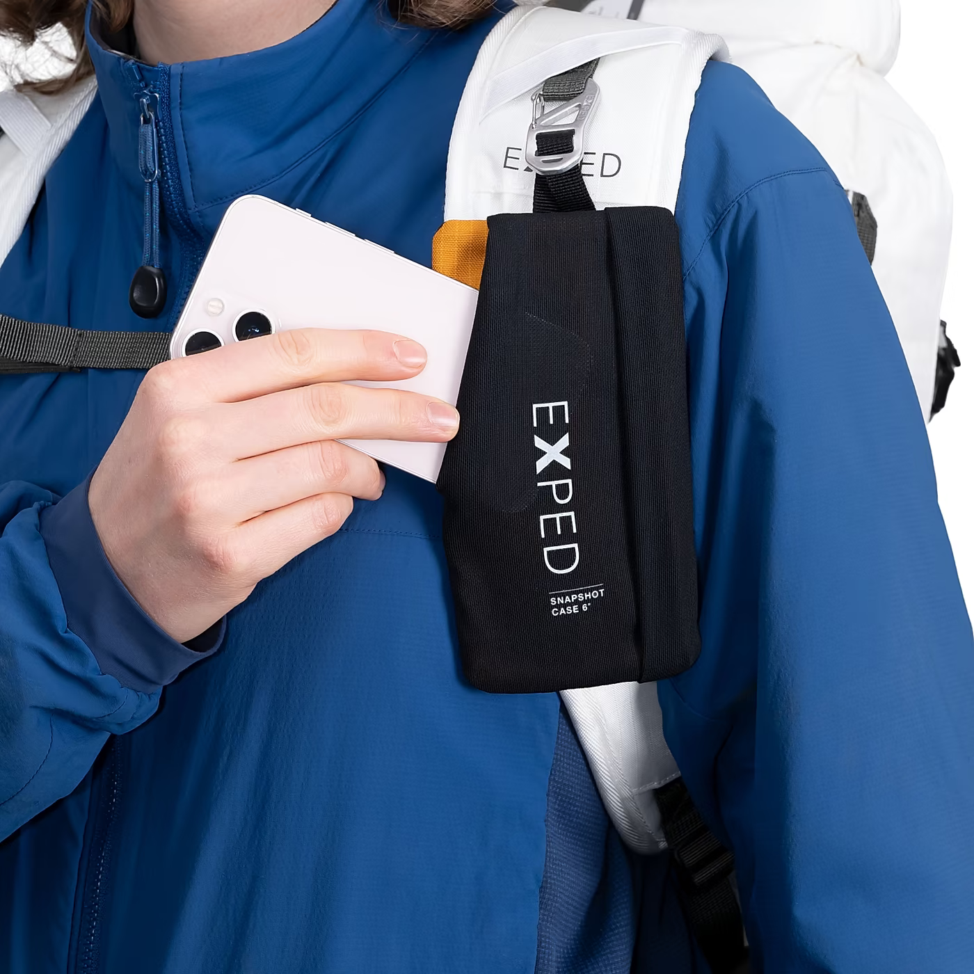 Person holding a phone case with an Exped backpack