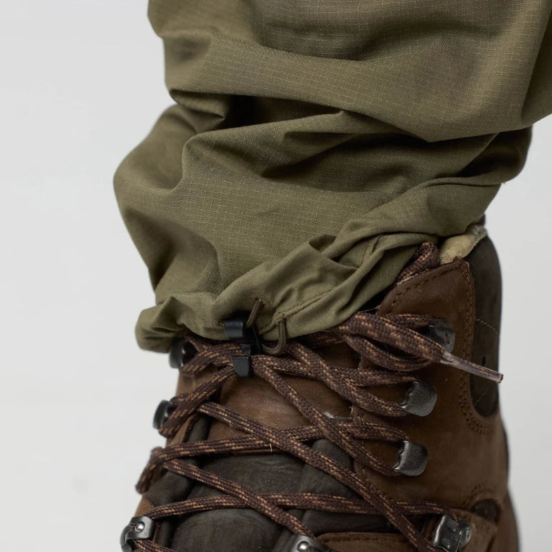 Brown leather boots worn with green pants on a white background