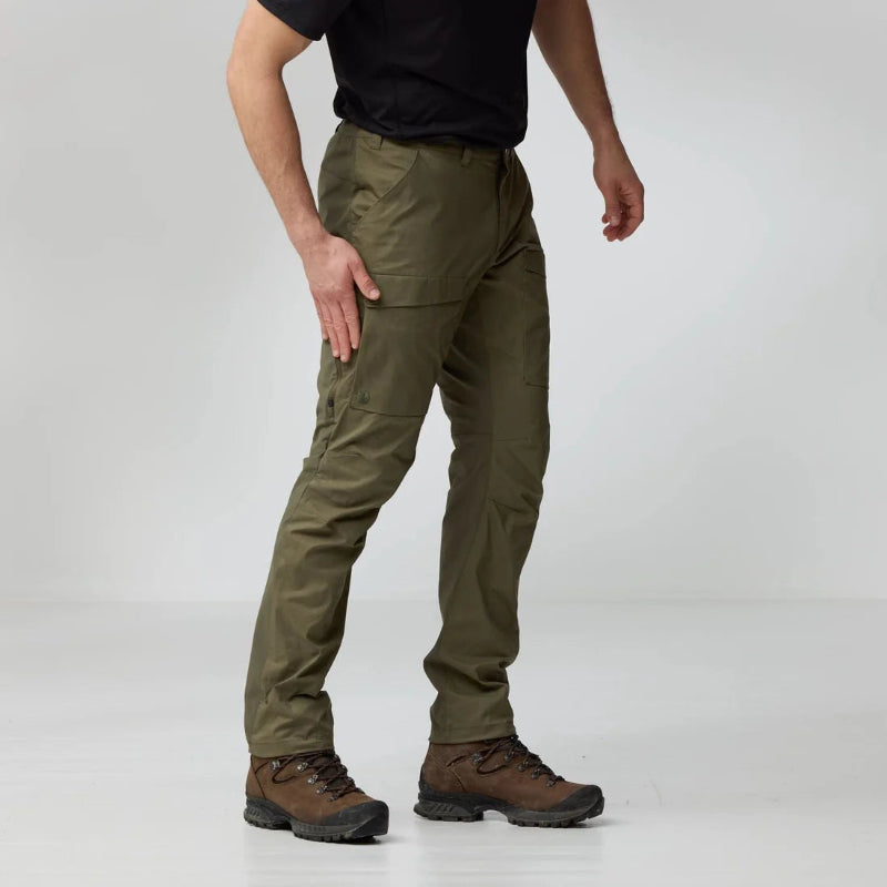 Person wearing olive green pants and brown boots on a white background