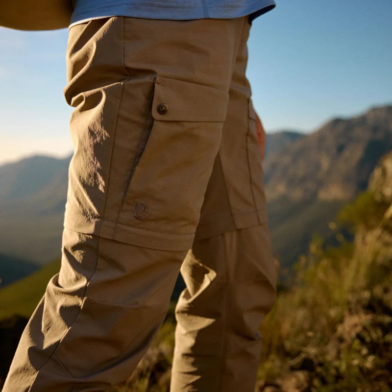 Person wearing beige pants with a mountainous landscape in the background