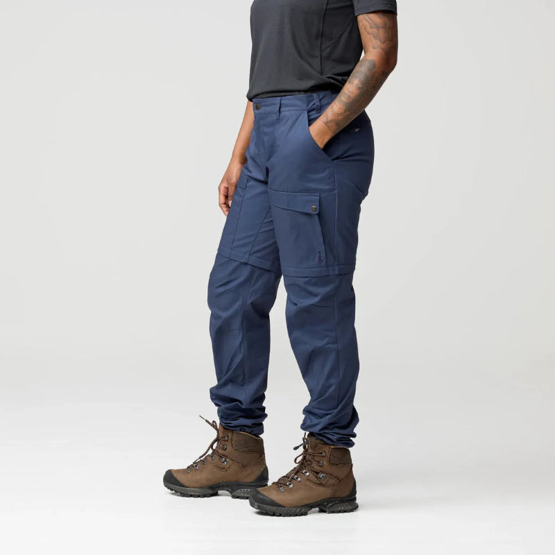 Person wearing blue cargo pants and brown boots on a white background