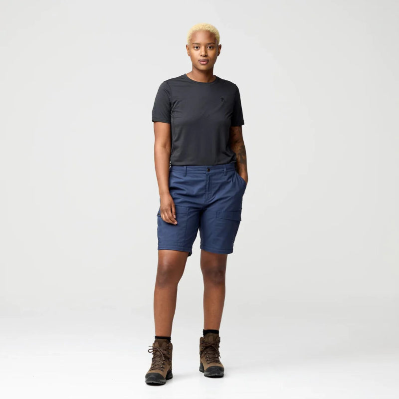 Person wearing a black t-shirt and blue shorts on a white background