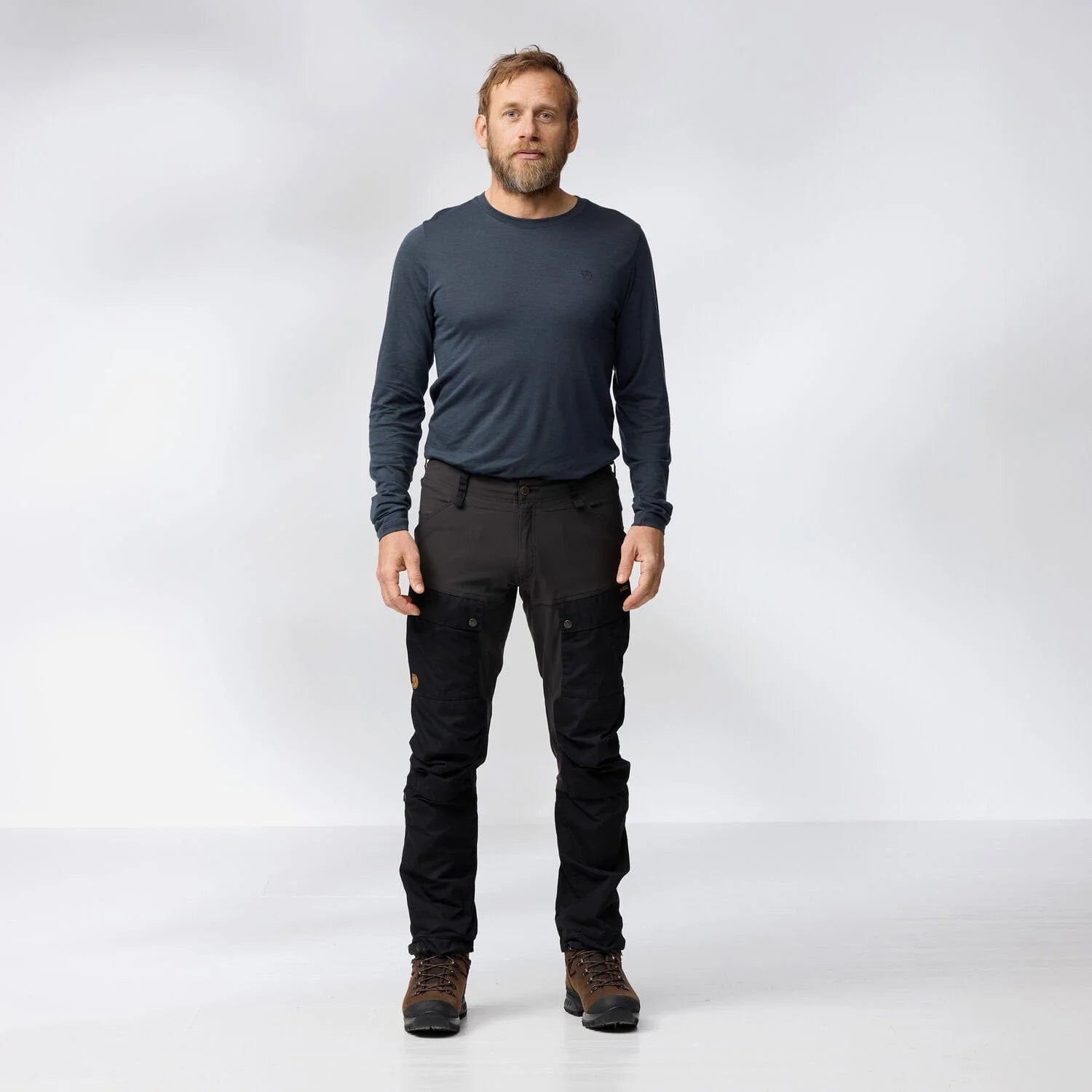 Man wearing a dark long-sleeve shirt and black pants on a white background