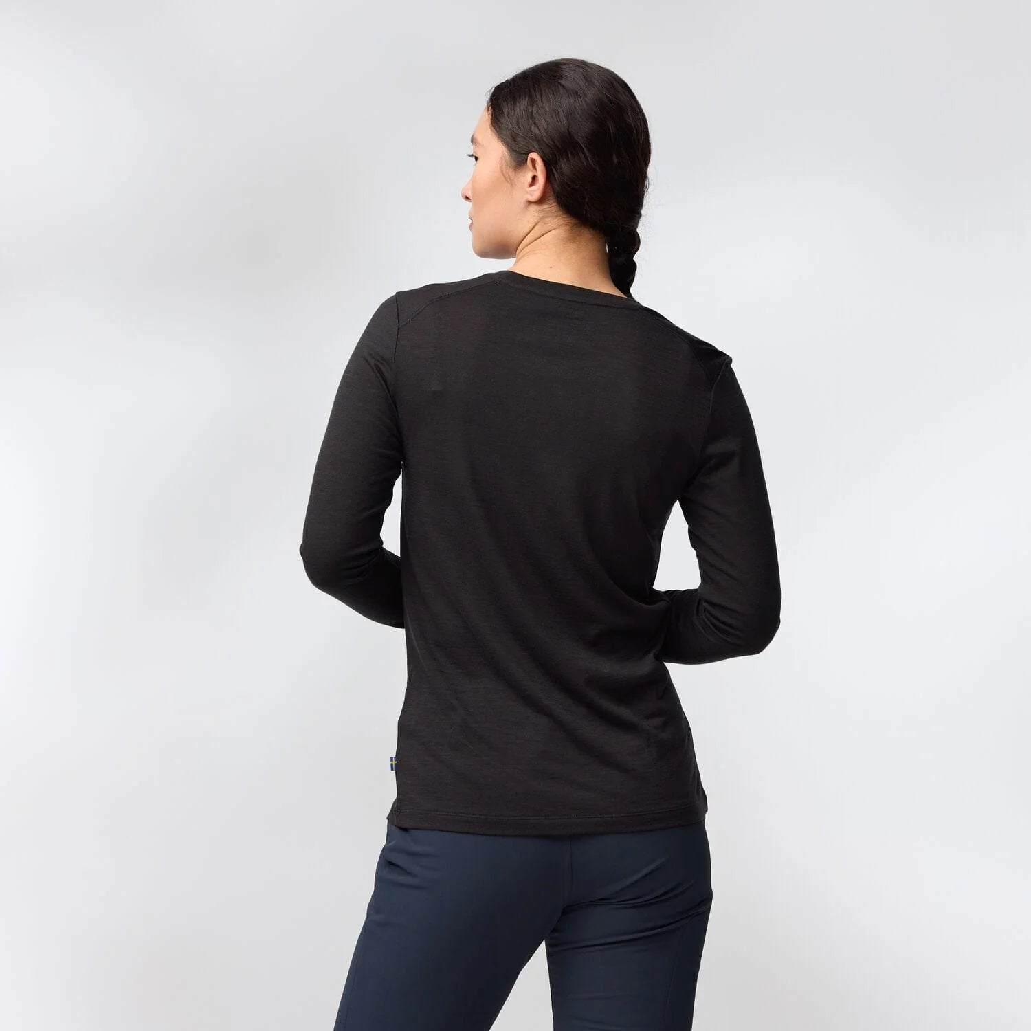 Person wearing a black long-sleeve shirt and dark pants on a white background