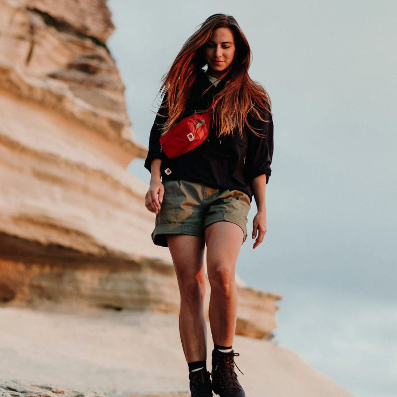 Woman walking on a coastal path with cliffs in the background wearing a fjallraven bumbag