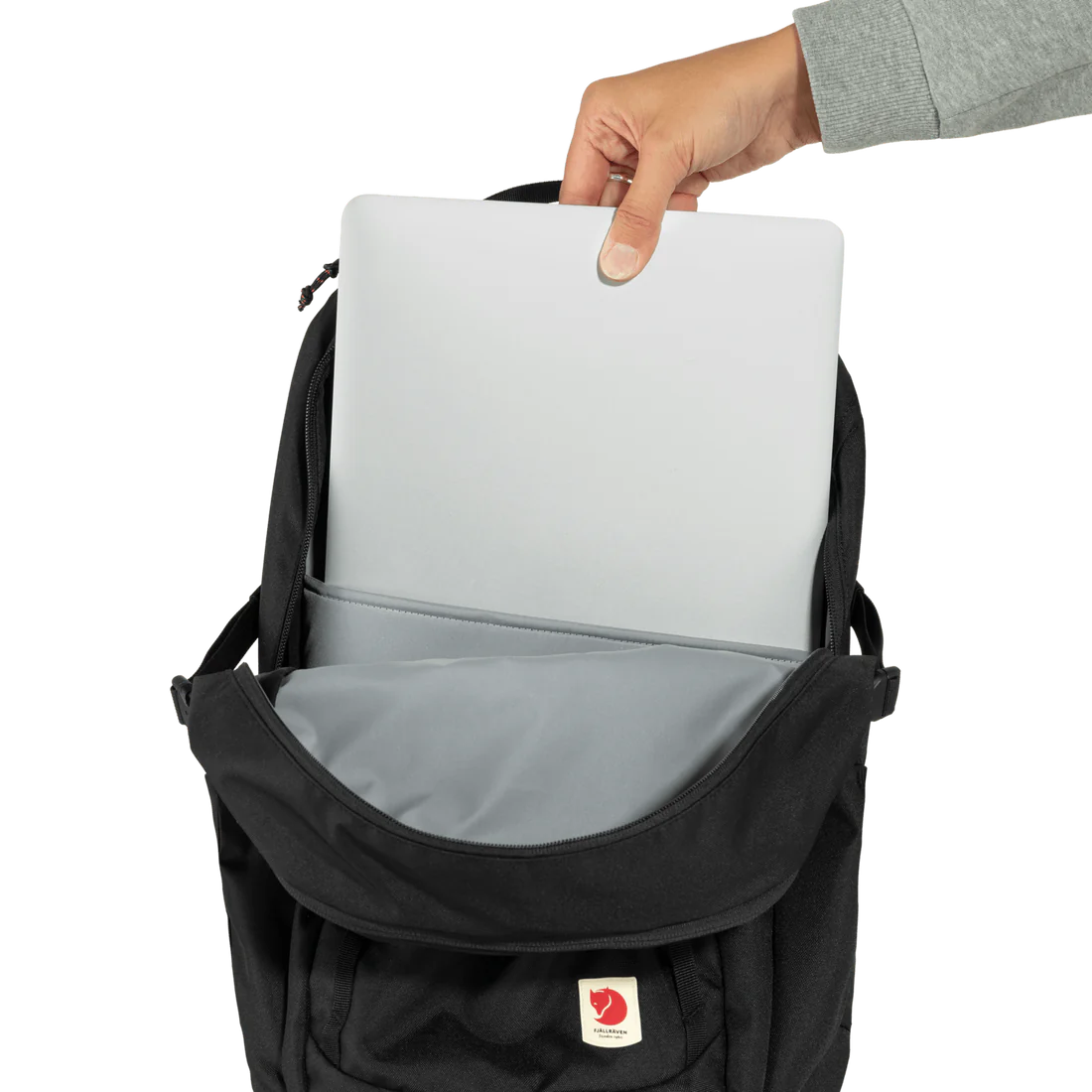 Hand pulling out a laptop from the laptop compartment of the backpack