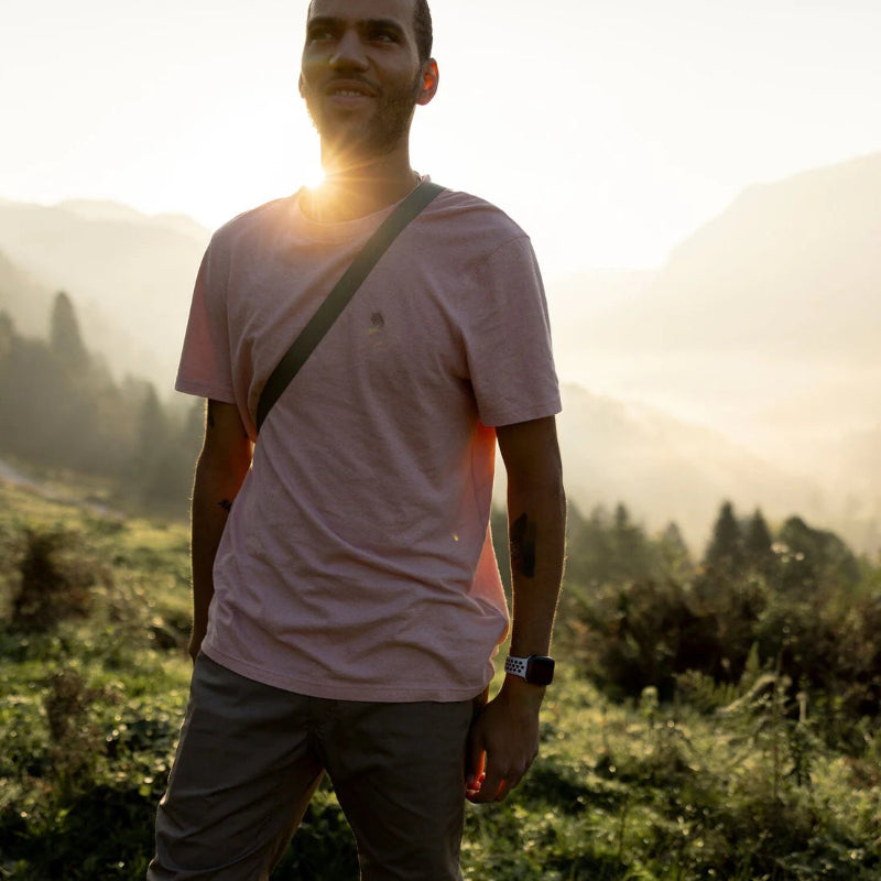Man standing in a field with mountains in the background during sunset.
