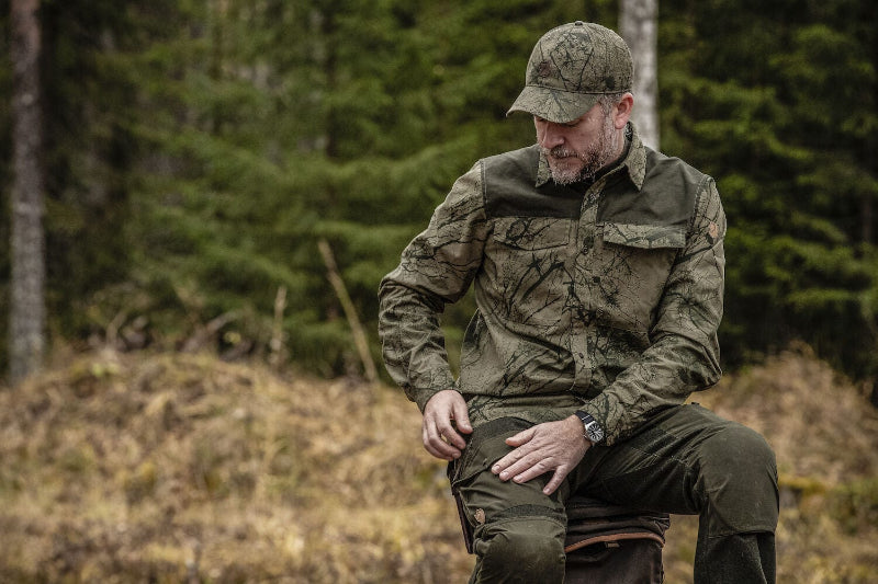 Man in camouflage clothing sitting in a forest
