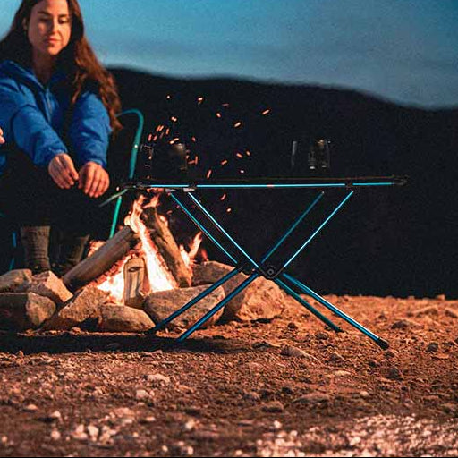 Two people sitting by a campfire in a desert landscape at night.