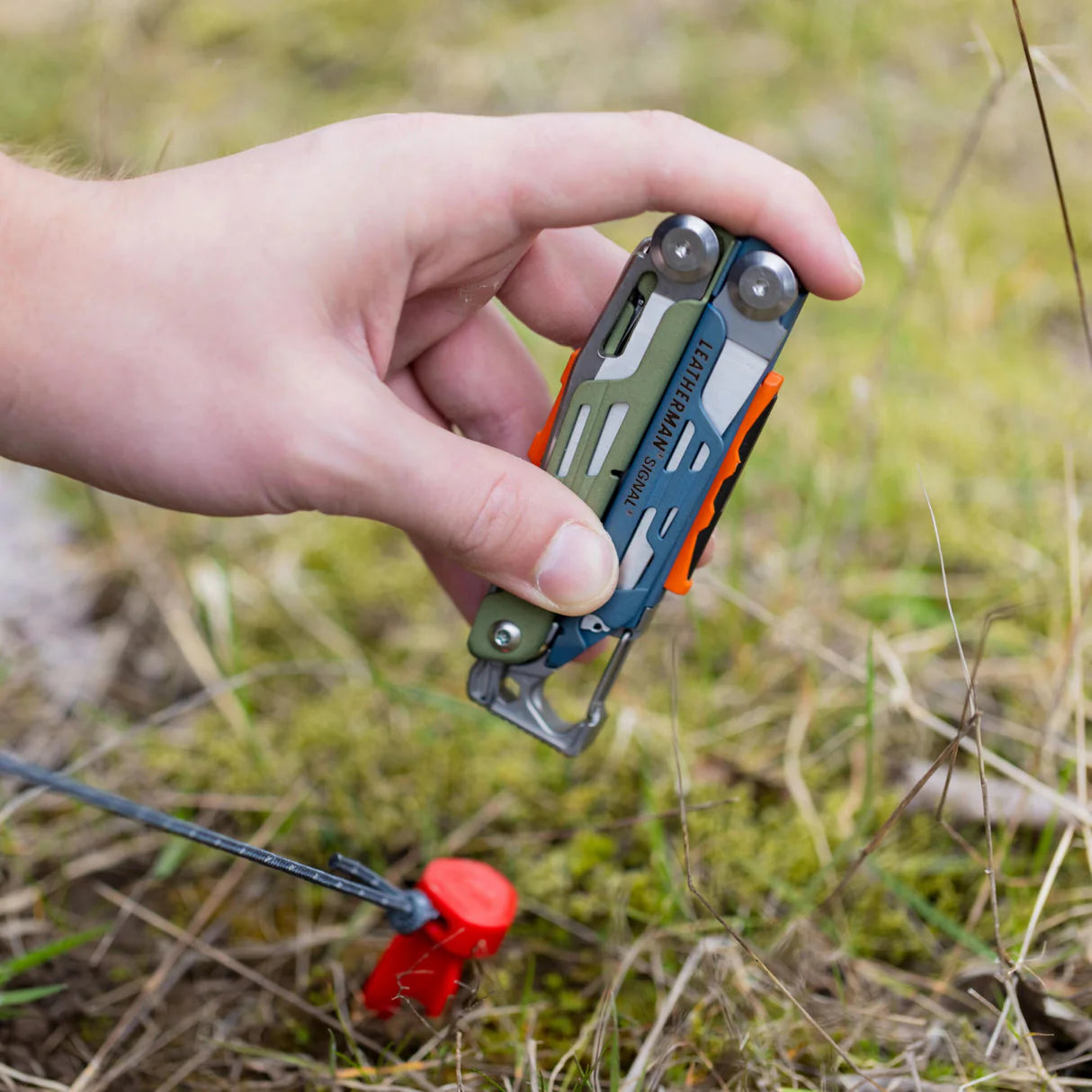 Hand holding a multi-tool in a natural outdoor setting