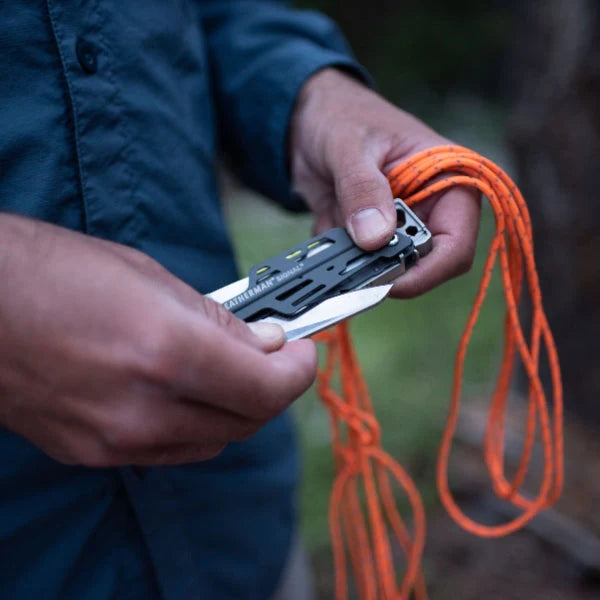 Person holding a multi-tool with an orange rope in a natural setting