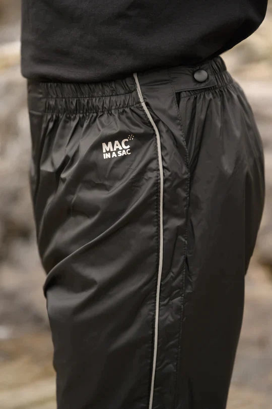 Side angle of a man wearing Mac in a Sac rain overpants with the logo in focus