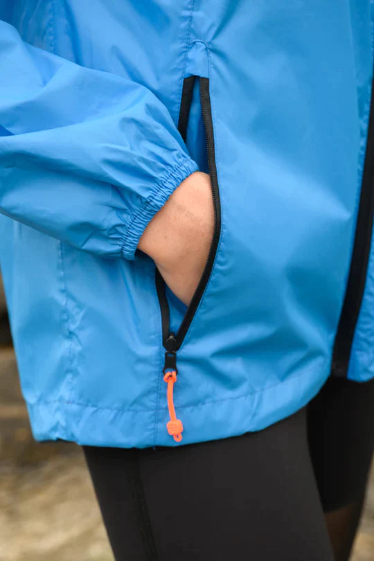 A womans hand tucked away in the pocket of her blue rain jacket