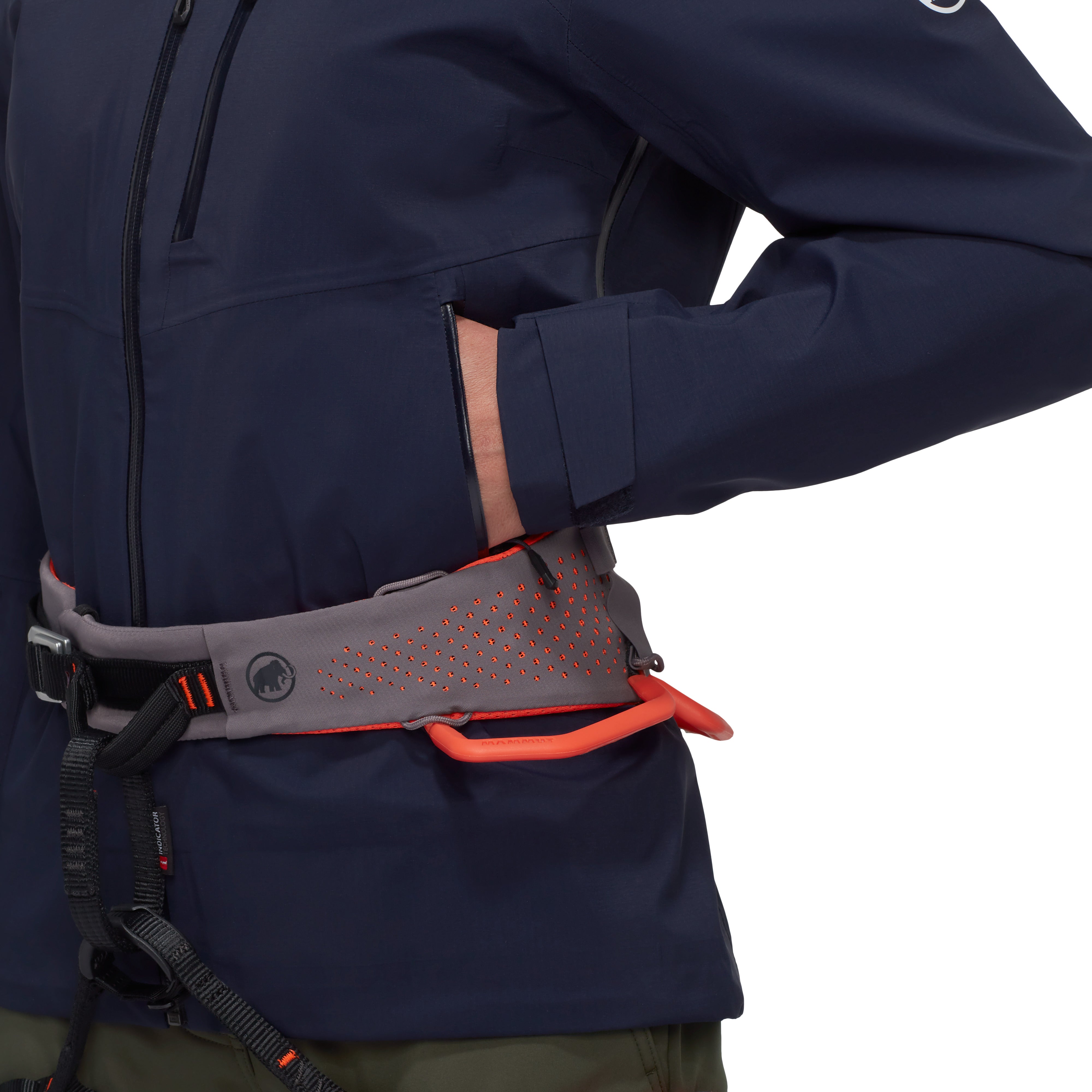 Person wearing a navy jacket with a gray and orange climbing harness on a white background