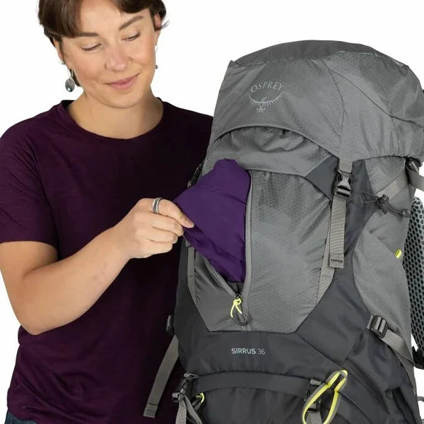 Person interacting with a gray Osprey hiking backpack on a white background