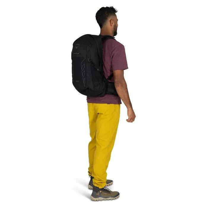 Man wearing a black backpack and yellow pants on a white background