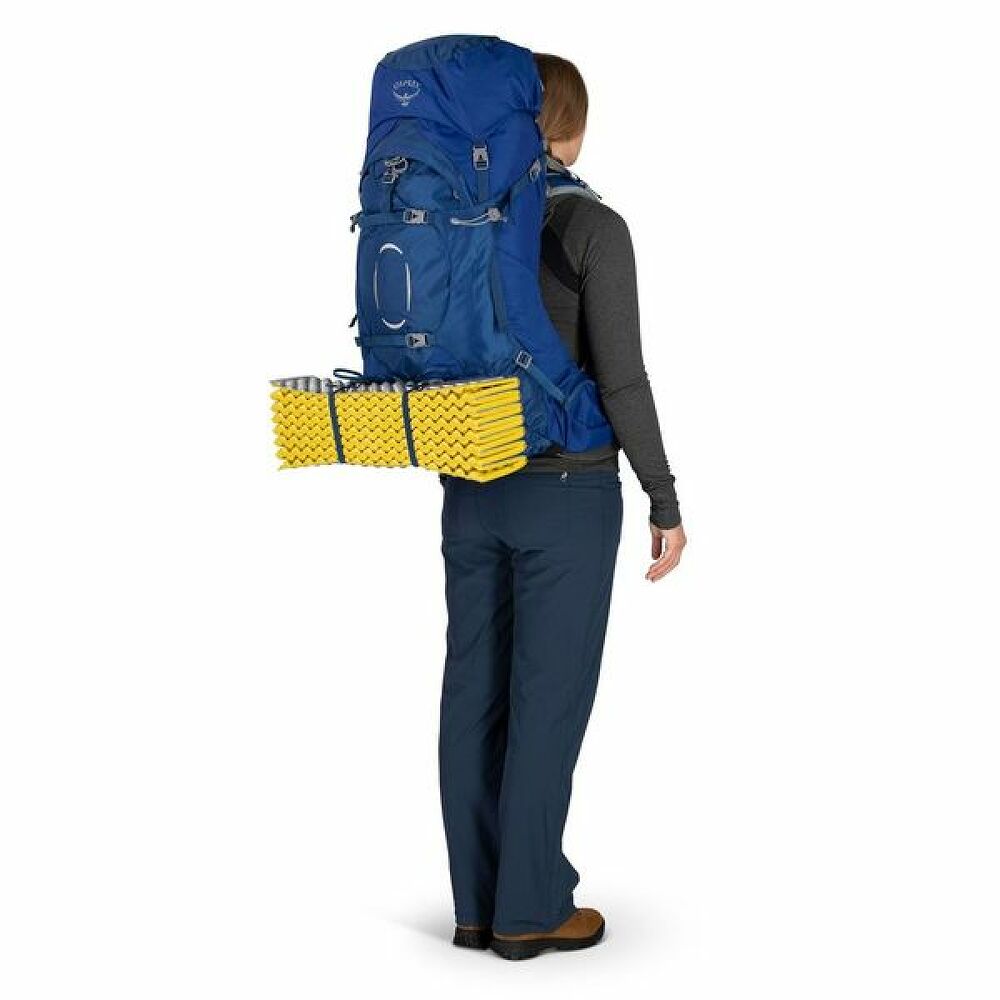 Person wearing a large blue backpack with yellow mat on a white background