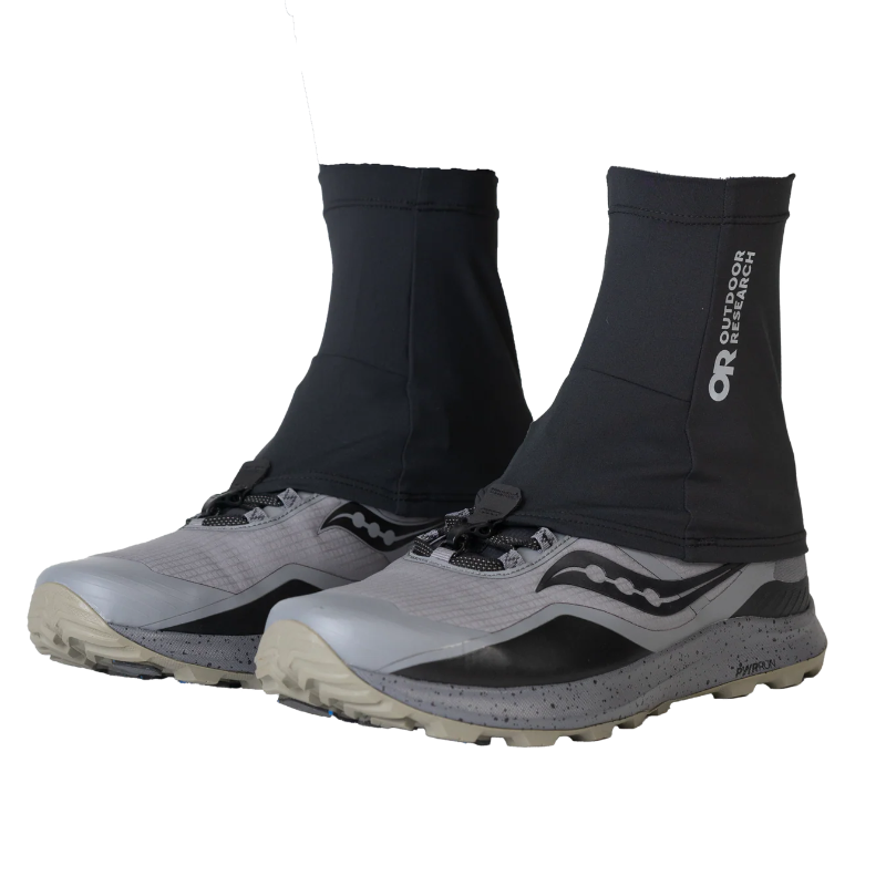 Black trail running gaiters on gray hiking shoes with 'Outdoor Research' branding on a white background