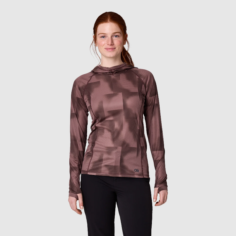 A woman modeling a long-sleeve athletic hooded top with a tonal geometric pattern in dusty mauve-brown, paired with black leggings, against a light gray studio background.