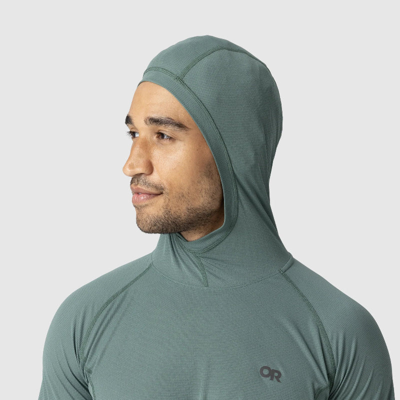 Man wearing a green hooded jacket with a visible brand logo on a light gray background