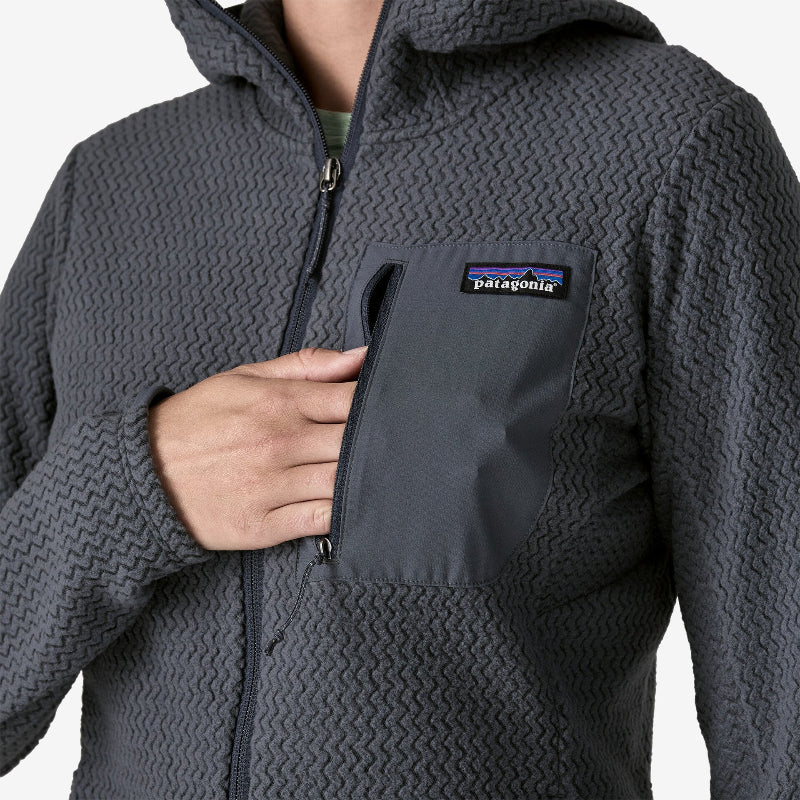 Woman putting her hand in the breast pocket of the Patagonia Women's R1 Air Fleece Full-Zip Hoody Smolder Blue