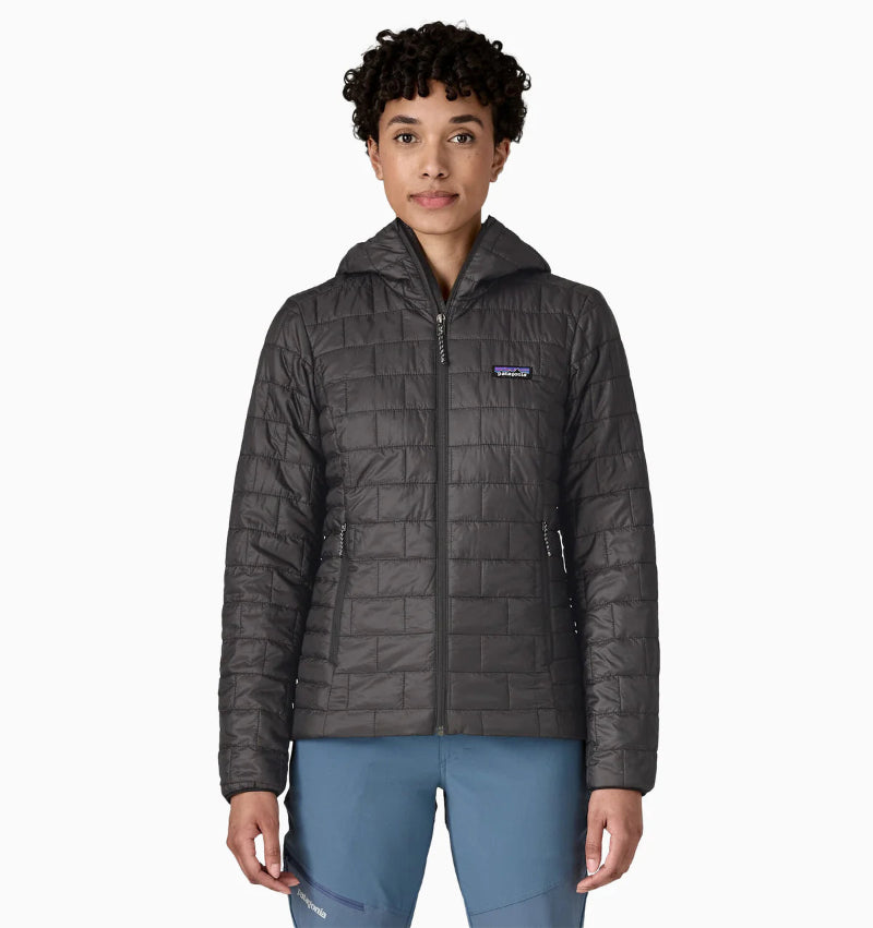 Person wearing a black quilted jacket with a brand logo on a white background