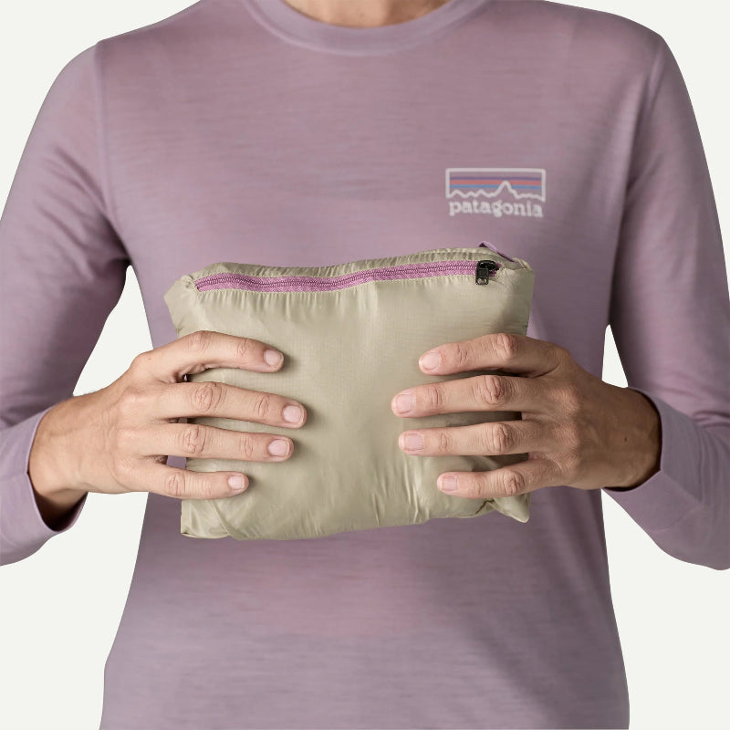 Person wearing a Patagonia shirt holding a Nano Puff stored in its pocket