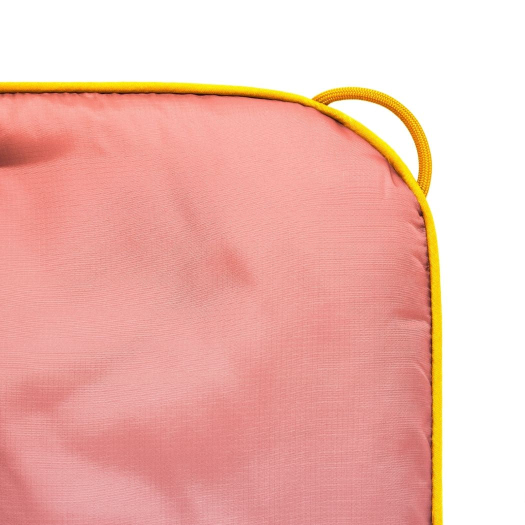 Close-up of a pink blanket with yellow piping on a white background