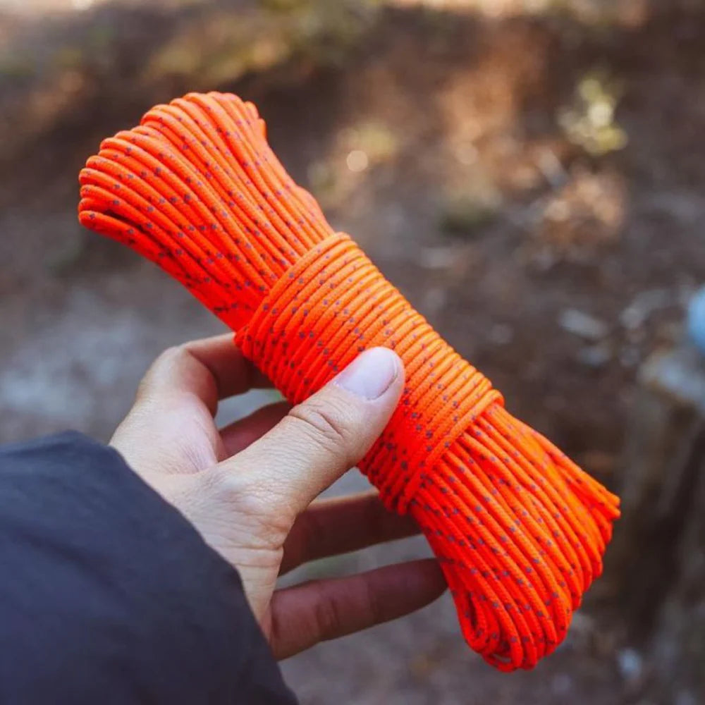 Hand holding a bundle of orange rope with a blurred natural background