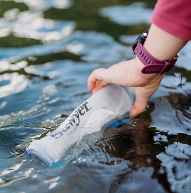 Sawyer Squeeze Water Filtration System w/ Cnoc 1L Bottle scooping up water