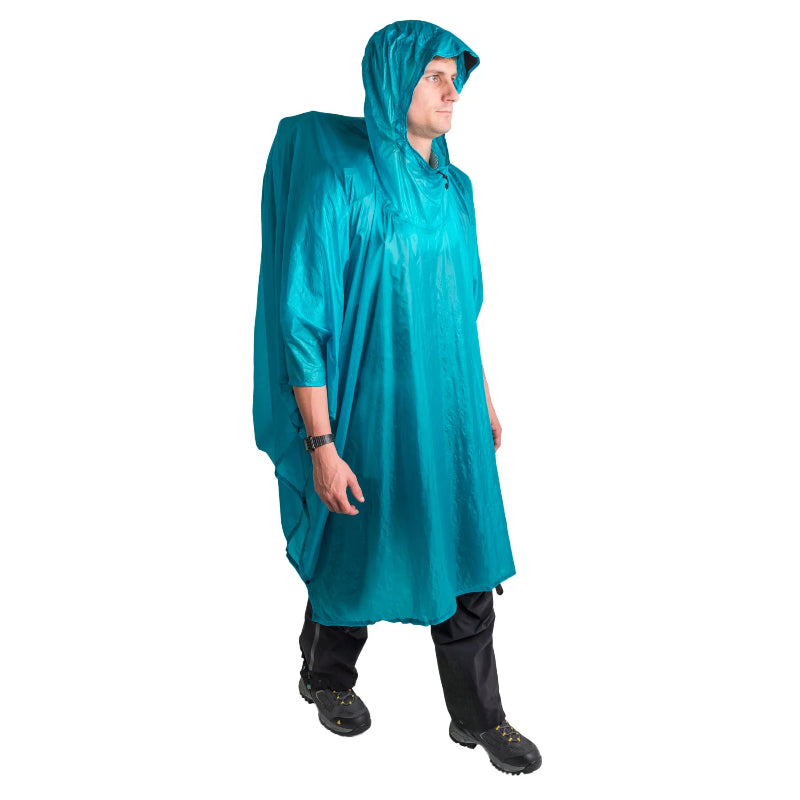 Person wearing a teal rain poncho on a white background