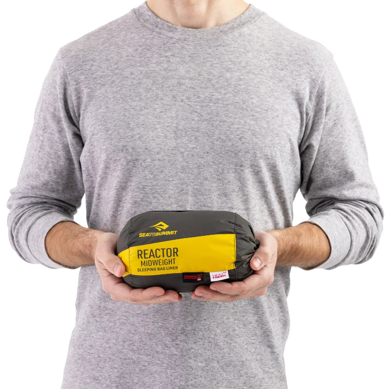 Person holding a Sea to Summit Reactor Midweight sleeping bag on a white background