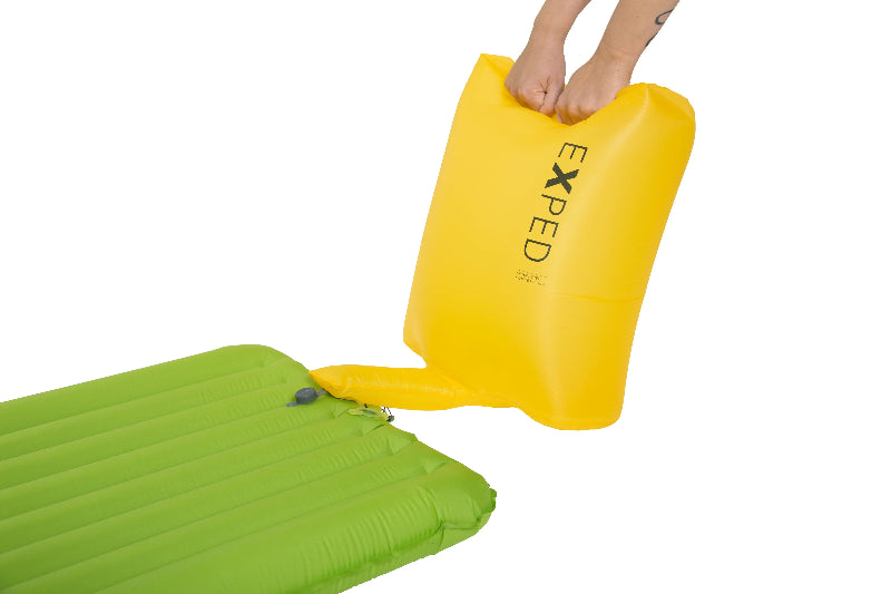 Yellow inflatable pad with 'Exped' branding being placed on a green air mattress.