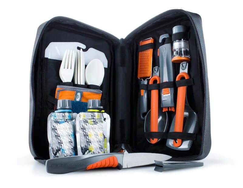 A set of kitchen utensils for camping in a fold out bag on a white background