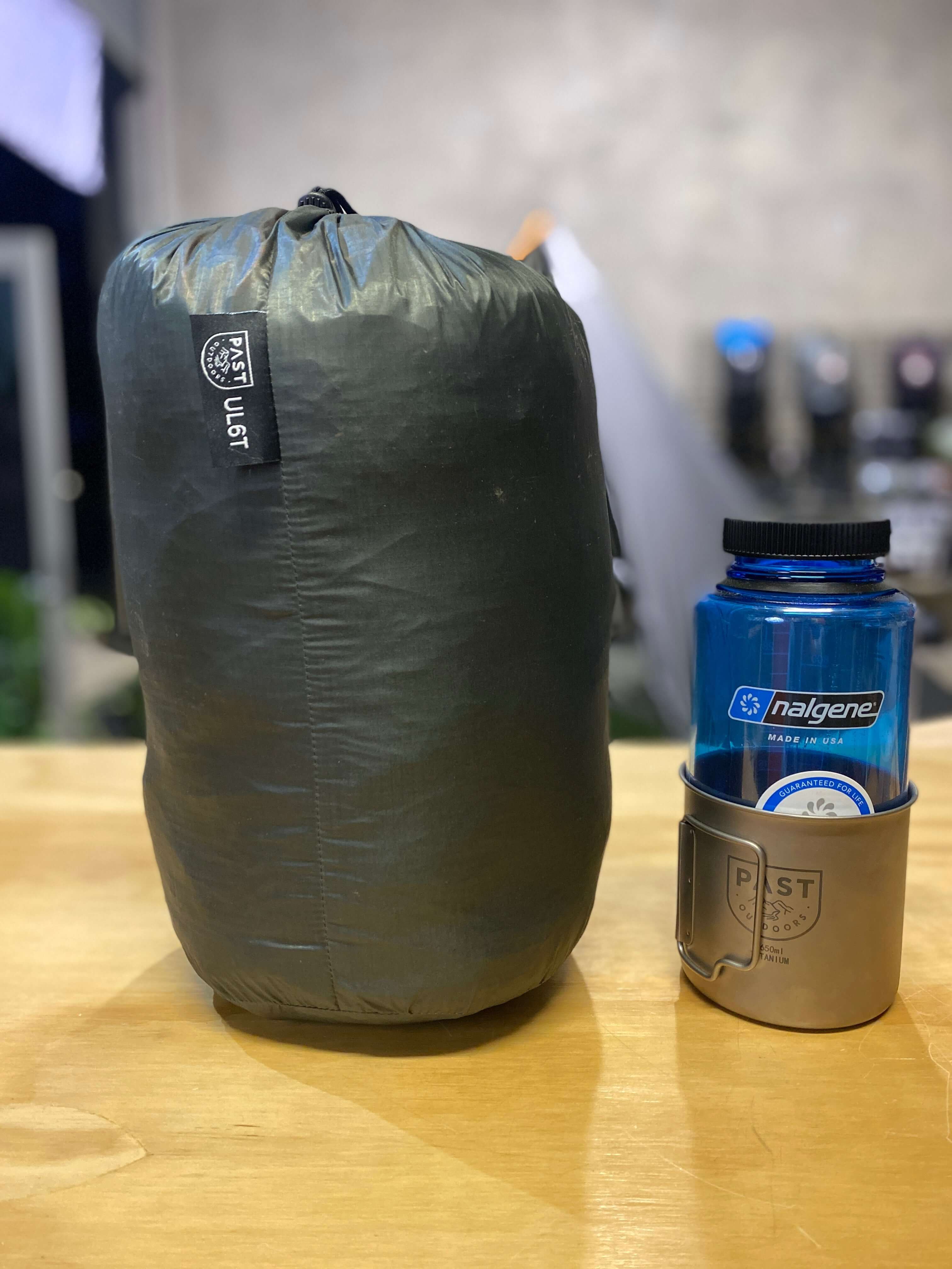 Tipi Tent in casing next to Titanium Canteen and blue Nalgene Water Bottle