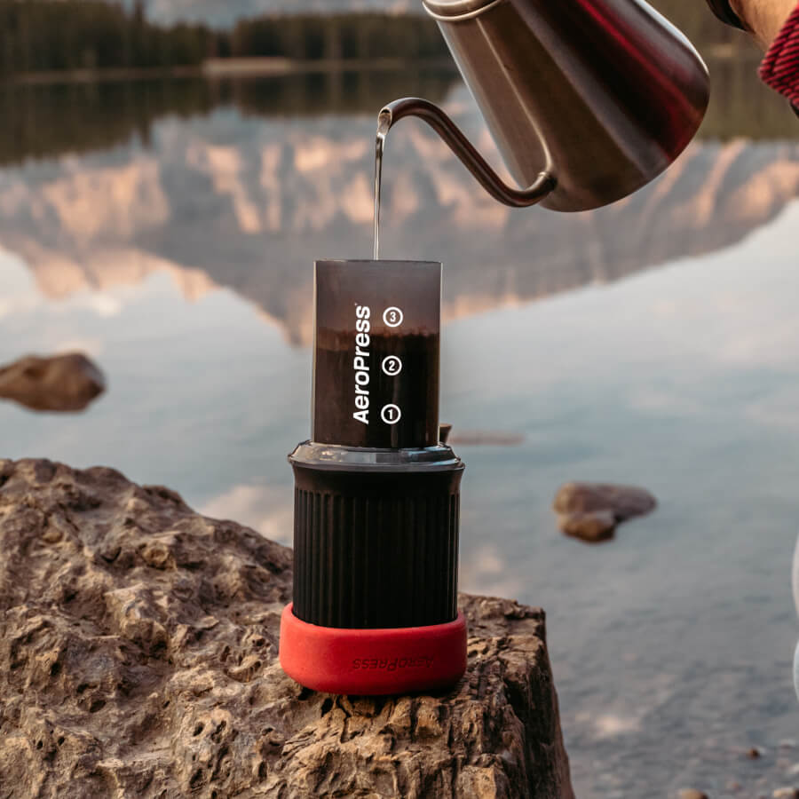 AeroPress Go -Travel Coffee Maker Kit being filled with water from a kettle by the lake