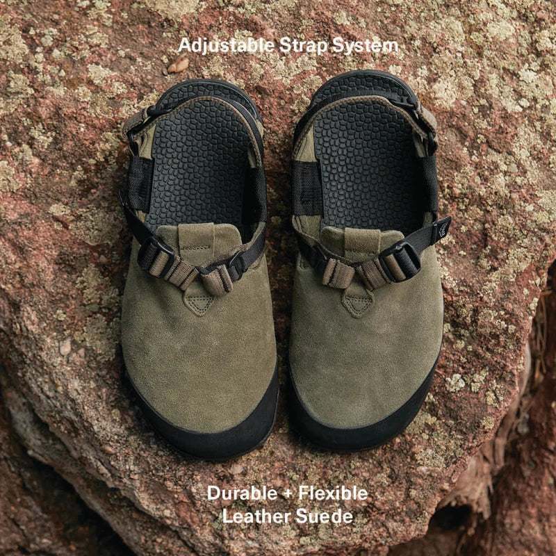 Pair of green shoes with adjustable straps on a rocky surface