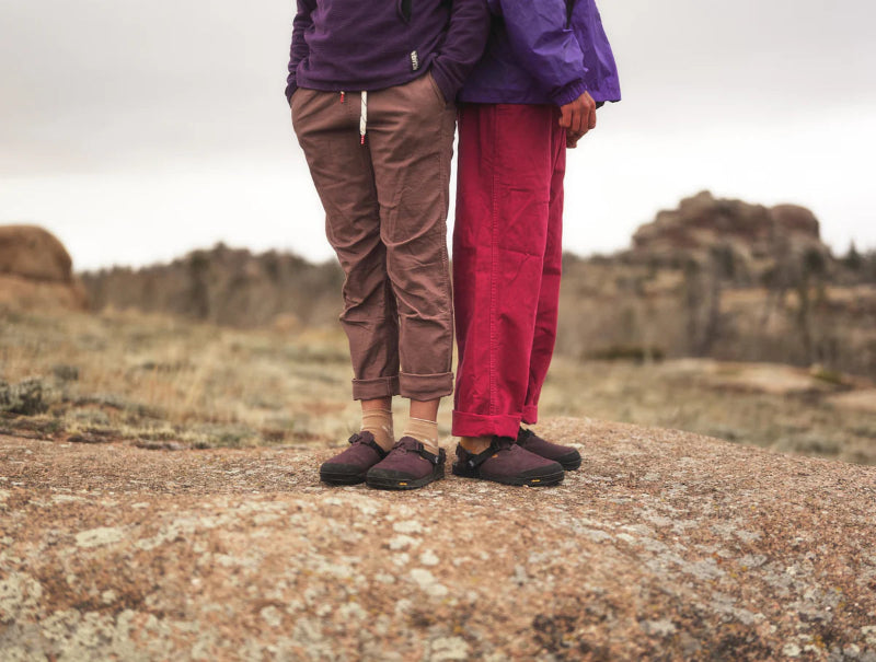 Two people standing on a rocky outcrop with a desert landscape in the background