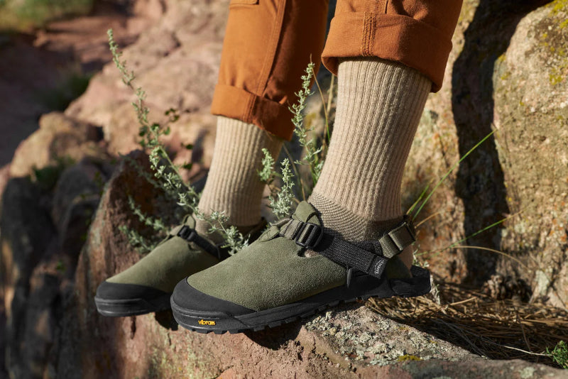 Person wearing green hiking boots with straps on a rocky terrain
